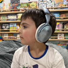 Load image into Gallery viewer, Child wearing headphones in a store with toy shelves in the background