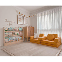 Load image into Gallery viewer, Children's room with orange sofa, bookshelf, and decorative elements.