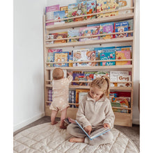 Load image into Gallery viewer, Two children in a room with a bookshelf filled with books.