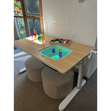 Load image into Gallery viewer, A children's adjustable wooden activity table with a light blue tray, shown in a room setting with a textured gray stool and carpet.