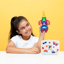 Load image into Gallery viewer, A young girl with her hair in a ponytail smiles while holding a colorful magnetic toy rocket. She is sitting at a white table against a solid yellow background, with a white metal storage box labeled 'CONNETIC' in front of her.

