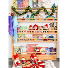 Load image into Gallery viewer, Wooden shelf with children's books, toys, and decorative items including Christmas-themed figures.
