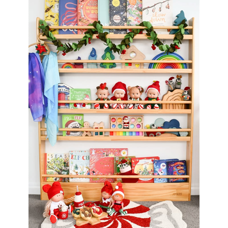 Wooden shelf with children's books, toys, and decorative items including Christmas-themed figures.