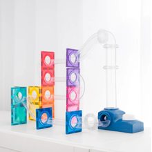 Load image into Gallery viewer, A colorful magnetic tile marble run toy set on a white surface against a bright white background. The set includes a blue base, clear plastic tubes, and translucent square tiles in teal, blue, pink, purple, red, and yellow.
