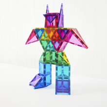 Load image into Gallery viewer, A colorful toy structure made of translucent magnetic building tiles arranged into a bird-like figure, standing on a white surface against a white paneled wall.
