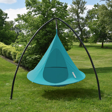 Load image into Gallery viewer, A teal hanging tree hammock suspended from a black curved metal frame on a grassy lawn with trees in the background.
