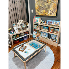 Load image into Gallery viewer, Children&#39;s play area with toy shelves, a small table with toys, and a colorful painting on the wall.
