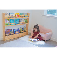 Load image into Gallery viewer, Child reading a book on the floor next to a bookshelf filled with children&#39;s books.
