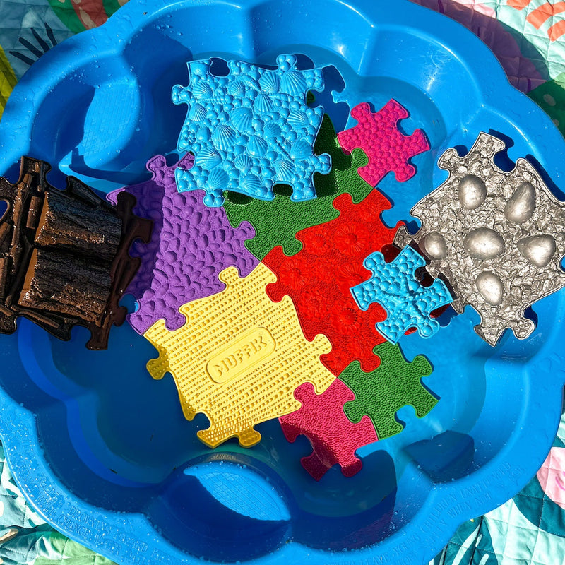 Colorful foam puzzle pieces in a blue tray with decorative items.