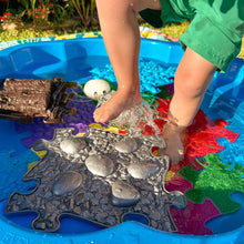 Load image into Gallery viewer, Child's feet playing in a wading pool with puzzle pieces and rocks.
